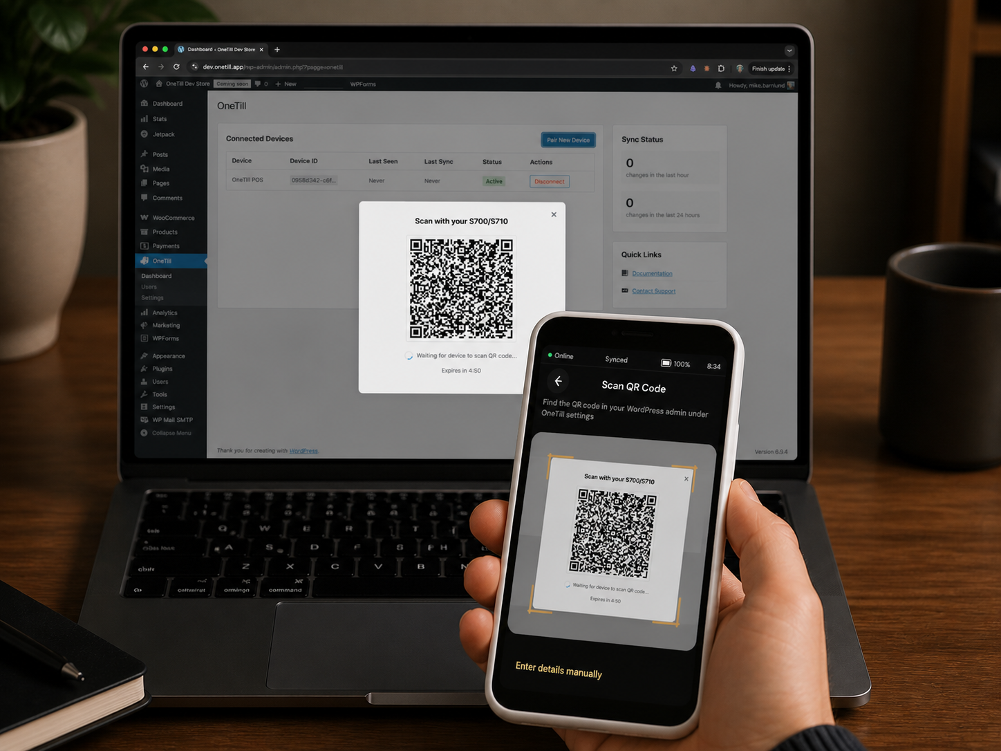 OneTill device scanning a QR code from a laptop screen to pair with WooCommerce